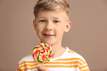 Cute little boy with lollipop on color background