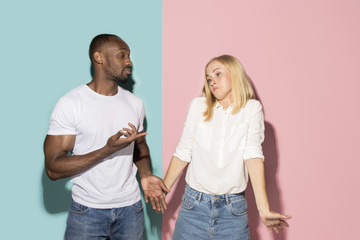 Beautiful female and male portrait on pink and blue studio backgroud. The young emotional couple