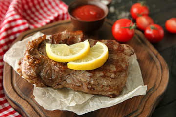 Tasty grilled steak with lemon on wooden board