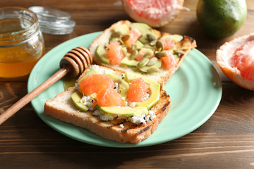 Plate with tasty toasts on wooden background