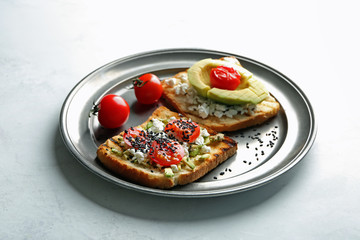 Plate with tasty toasts on light background