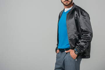 cropped image of man in stylish outfit posing with hands in pockets isolated on grey background