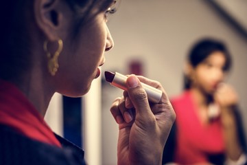 Indian woman putting on a lipstick