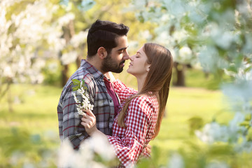 Happy young couple near blooming tree in park on spring day