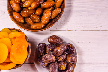 Date fruits and dried apricots on wooden table. Top view