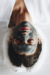 Woman relaxing with a charcoal facial mask