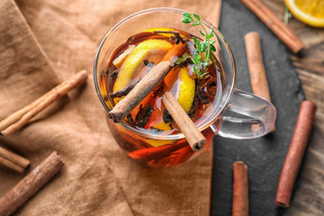 Cup of hot aromatic beverage with cinnamon and lemon on table