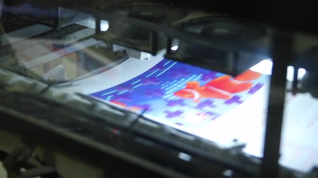 A magazine gets processed through a large industrial printing press.