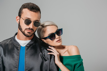stylish couple posing in sunglasses for fashion shoot, isolated on grey