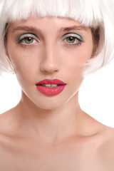 Young woman with wig and professional makeup on white background, closeup