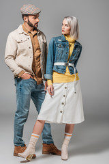 couple posing in autumn outfit and looking at each other, on grey