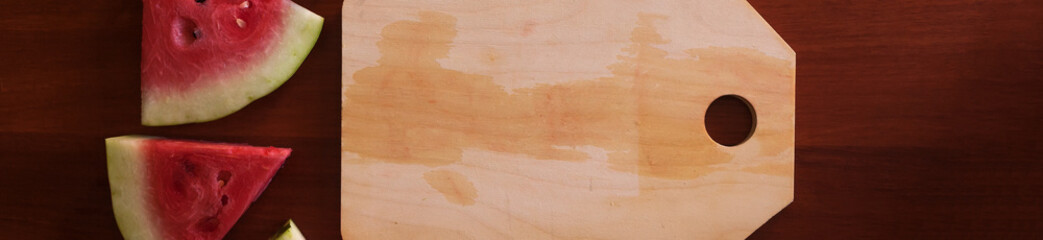 Watermelon pieces and cut board placed on wooden background. Copy space