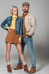 attractive couple posing in autumn outfit for fashion shoot, on grey