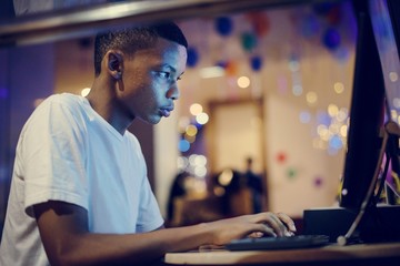 African american boy using a computer at night - obrazy, fototapety, plakaty