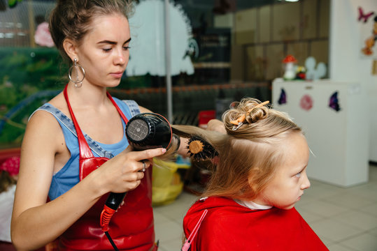 Woman cuts the baby hair. The girl is afraid to cut hair. He closed his eyes with fear. The background image place for text.