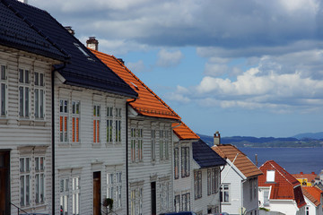 A number of wooden houses with a tiled roof on a street in Norway