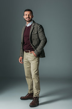 elegant male model posing in beige pants and tweed jacket, on grey