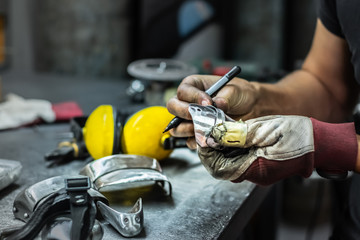 Male metal worker constructing and assembling piece of medieval armour suit. Man hands working with...