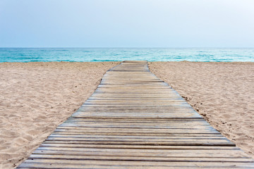 Wooden boardwalk at beach in sand and sea in the background - obrazy, fototapety, plakaty