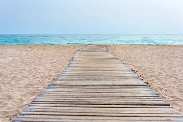 Foto op Plexiglas Afdaling naar het strand Houten promenade aan het strand in zand en zee op de achtergrond