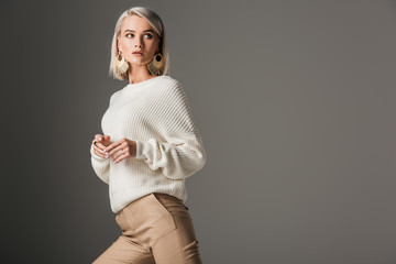 elegant blonde model posing in white knitted sweater, isolated on grey - obrazy, fototapety, plakaty
