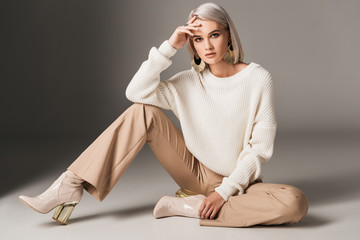 attractive fashionable woman posing in white trendy sweater, beige pants and autumn heels, on grey - Powered by Adobe