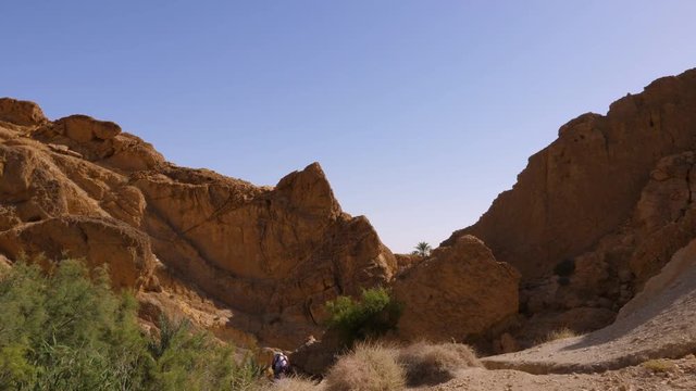 Tourist people walking through sandy canyon in Oasis Chebika in Sahara desert