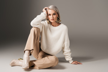 elegant beautiful girl posing in white sweater and autumn heels, on grey