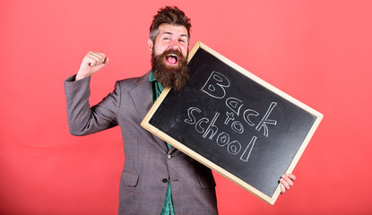 Continue education private school. School and studying concept. Teacher or educator welcomes students while holds chalkboard with inscription back to school. Teacher begin first lesson after holidays