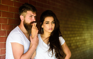 Couple in love hugs while smoking cigarette brick wall background. Couple find place to hide from witnesses, smoking cigarette in tranquility. Break or pause for smoking. Share single cigarette