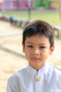 Portrait of Asian boy Wearing a white shirt in the grass.