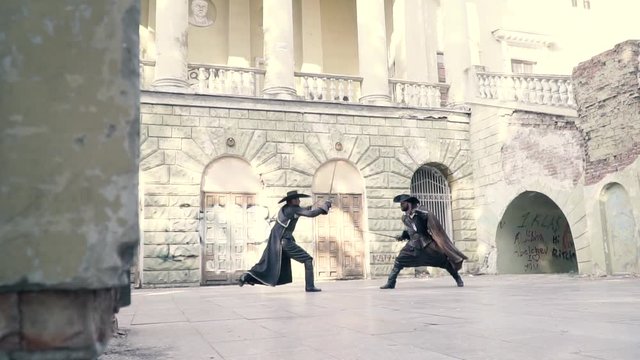 Two musketeers cosplay the musketeers and fight on swords