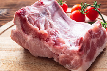 raw meat lying on a wooden table spices cherry tomatoes red pepper on the Board cut cooking