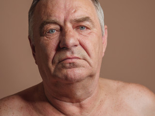 Aged man portrait on light background.