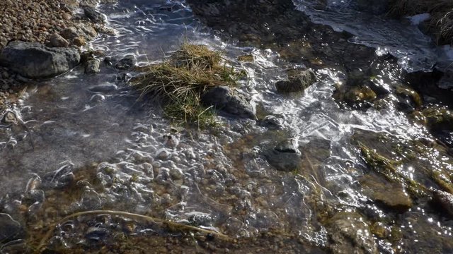 Flowing water of a semi frozen , ice river in the hills of Devon County, England