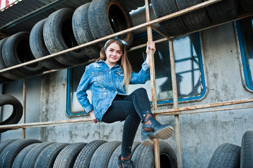 Young hipster girl in jeans jacket and head scarf at tire fitting zone.