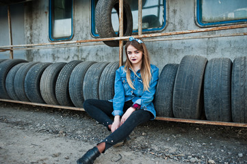 Young hipster girl in jeans jacket and head scarf at tire fitting zone.