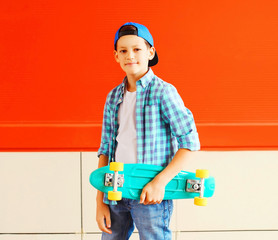 Fashion portrait stylish teenager boy holds skateboard on a red background