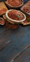 Uncooked Red rice in a bowl with a wooden spoon