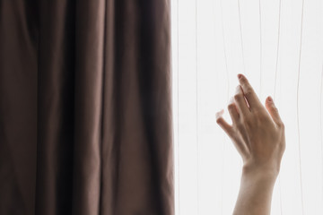 Female hand opens the window curtains