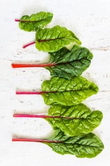 fresh chard leaves on a white old wooden table