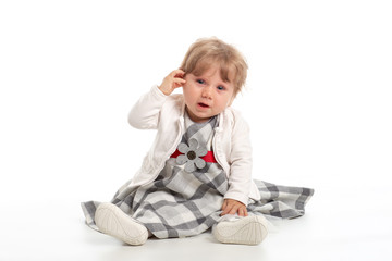 Elegant baby girl 1 year old sitting on the studio floor. White Background.