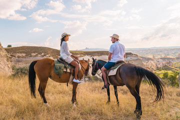 happy young couple on vacation Turkey Kapadokya horse riding in the mountains with hot air balloons on the background of Cappadocia Goreme