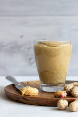 Fresh made creamy peanut butter in a glass jar and knife.