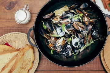 mussels in white cream sauce with bread and herbs