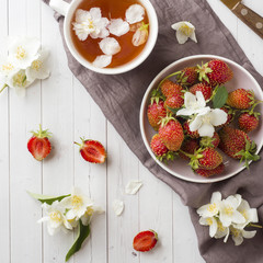 Obraz na płótnie Canvas Fresh strawberries and tea with Jasmine flowers on a light background. Summer concept