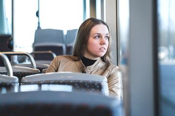 Serious woman in train or bus looking through the window. Thoughtful passenger in public transportation. Upset lady traveling.