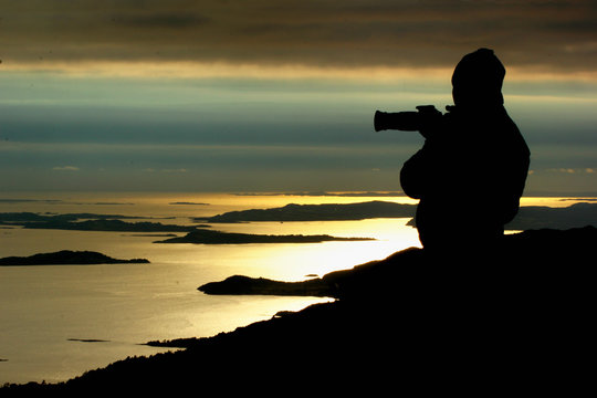 Silhouette of a photographer looking at sunset near Preikestolen, Norway