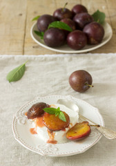 Ice cream with caramelized plums and ripe plums on a wooden background. Rustic style.