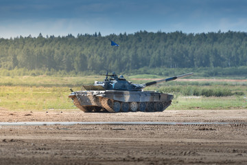 Fototapeta premium Military armored tank driving in mud at the open field